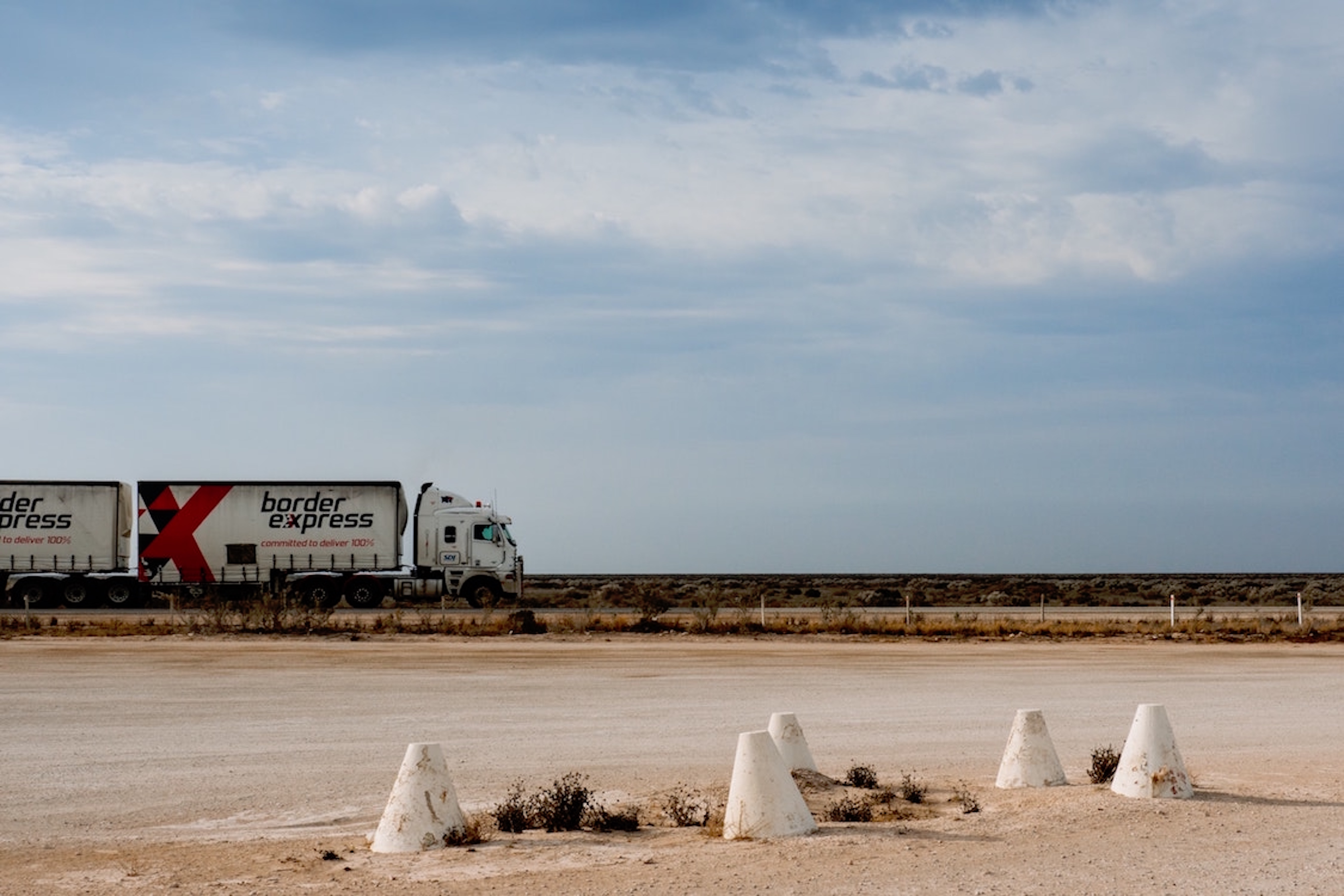 Cargo freight Semi-truck driving on a flat road in the desert with blue skies